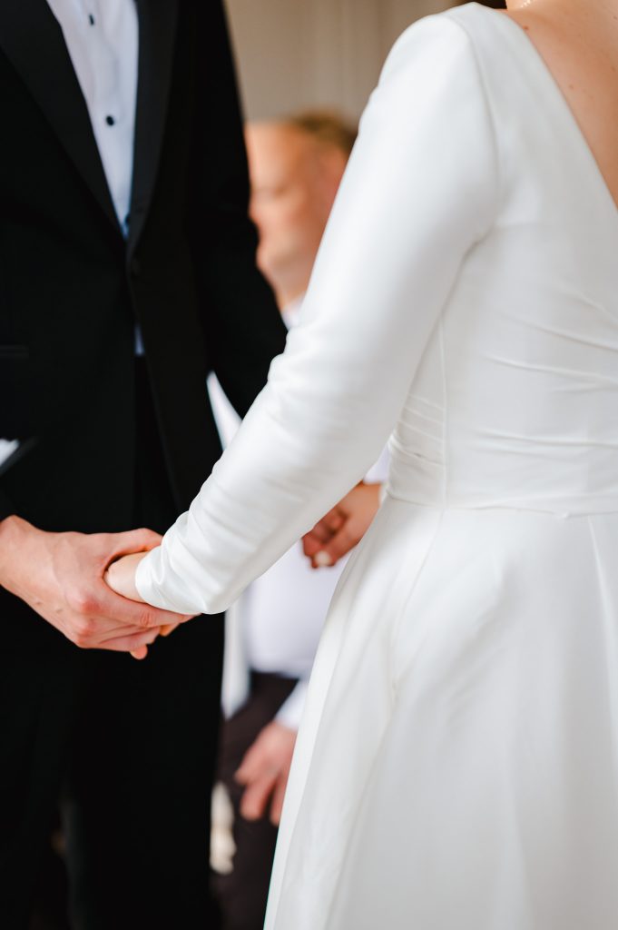 Bride and groom holding hands during their wedding ceremony at Rockbeare Manor